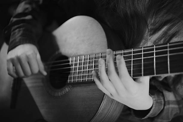 black and white hobby and professional music training, professional guitar music cinematic. Teenager's hands plays guitar. classical music