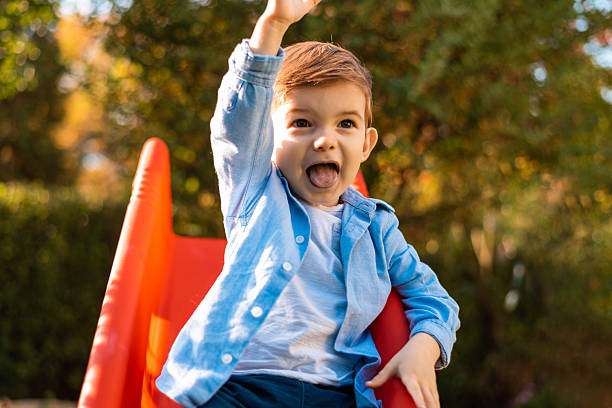 A happy kid boy playing on a slide on the park playground. High quality photo
