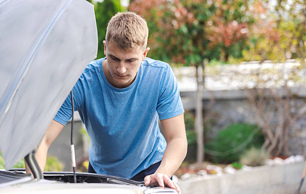 istock Man Inspecting Car Engine in Outdoor Setting During Daytime 2210628847