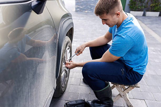 istock Mechanic Fixing a Car Wheel Outdoors on a Sunny Day 2210628865