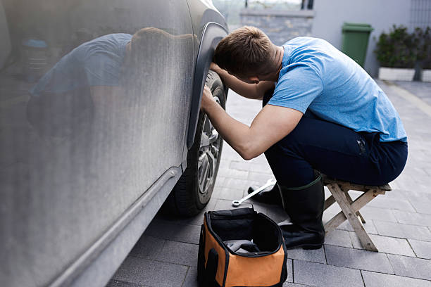 istock Man Repairing a Car Tire Outdoors With Tools and Equipment 2210628891