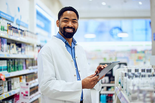 istock Smiling Pharmacist Holding a Tablet in a Well-Organized Pharmacy 2210629021