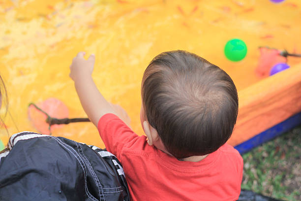 istock Asian toddler is playing outdoors and catching fish in an artificial pond. 2210629178