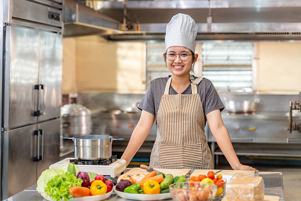 istock Smiling Female Chef in Kitchen with Fresh Vegetables on Counter 2210647276