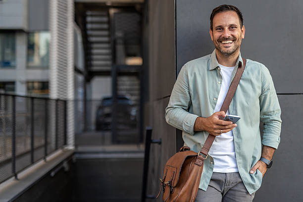 istock Smiling businessman using phone outside office building 2210651647