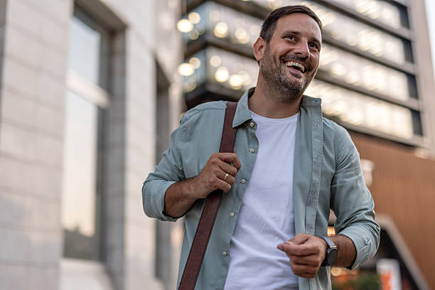 istock Smiling businessman walking near modern office buildings 2210652949
