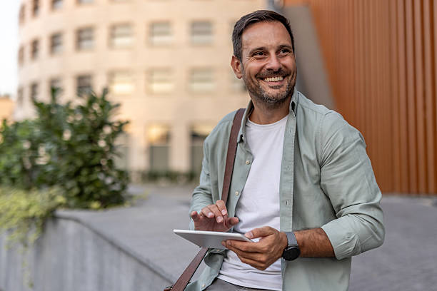 istock Smiling mid adult man using digital tablet outdoors 2210652993