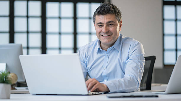istock Professional man working on a laptop with a smile in a modern office space environment. 2210661430