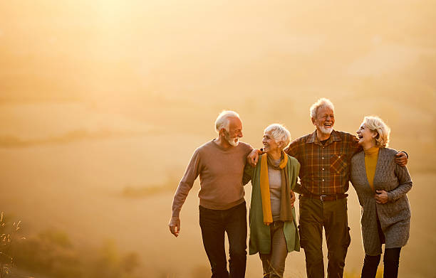 istock Happy mature couples talking while walking embraced in autumn day at sunset. 2210661677