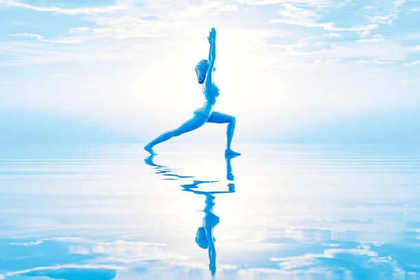 Woman practicing yoga outdoors balancing on weathered wooden structure against a blue sky