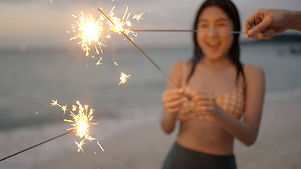 istock Group of friends having fun on the beach with fireworks 2210667335