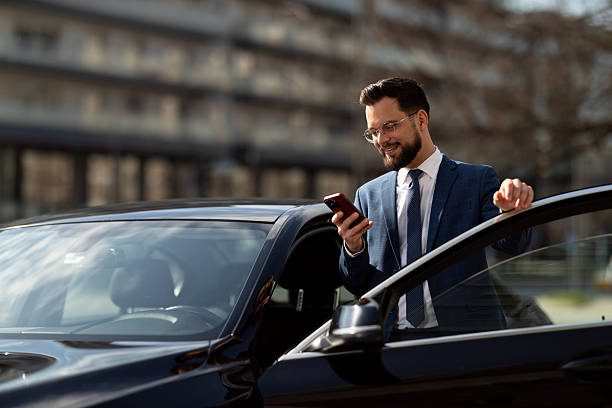istock Businessman Checking Smartphone Beside CarDescription: 2210668183