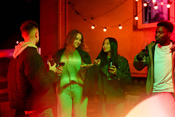 istock Friends enjoying an evening gathering with drinks and conversation in a warm, festive atmosphere 2210671085