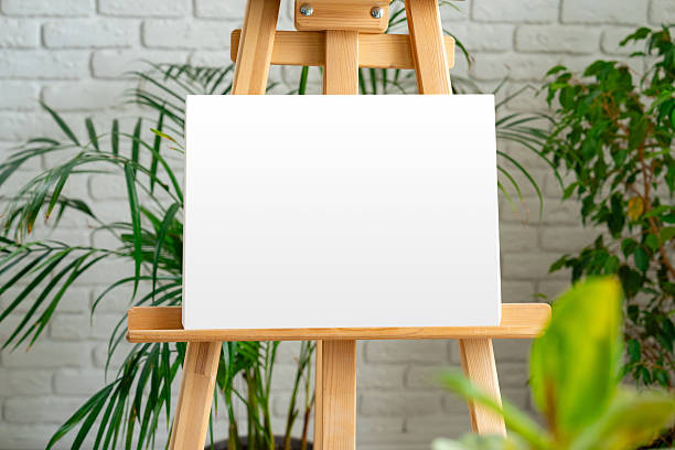 istock Blank canvas on an easel surrounded by greenery in a bright, modern art studio 2210671104
