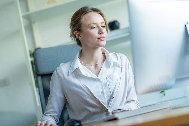 istock Professional woman working at a desk with a computer in a bright, modern office environment during the daytime 2210673895