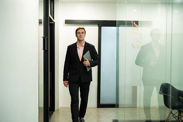 istock Business professional walking confidently in a modern office corridor during daytime hours 2210676108