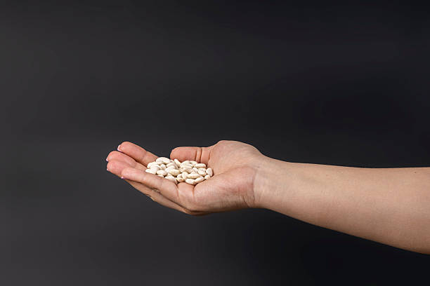 istock a handful of white beans in hand on a dark background 2210678840