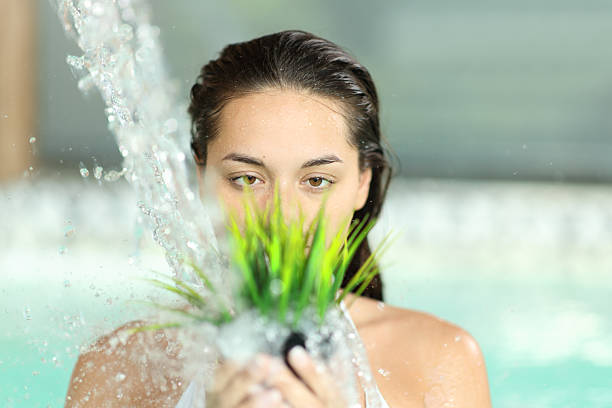 Crazy woman watering plastic plant with a water jet in a spa pool