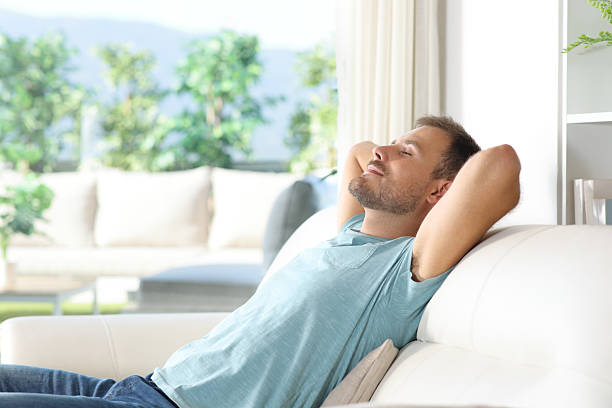 istock Man relaxing sitting on a couch beside a window with nature views 2210678916