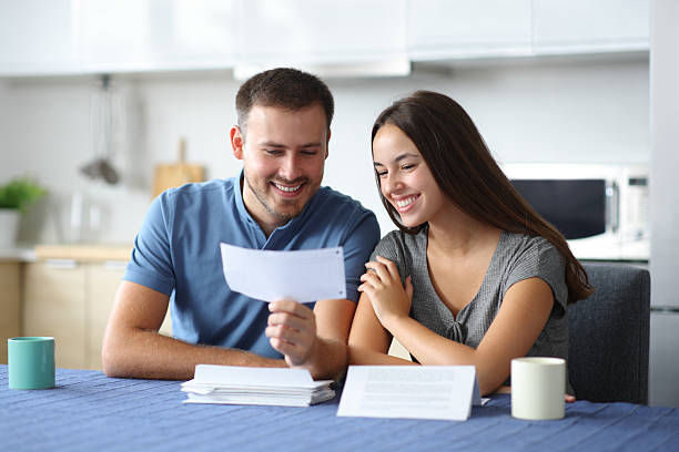 istock Happy couple checking bank statement in the kitchen 2210679146