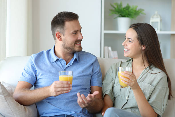 Happy couple talking and drinking orange juice