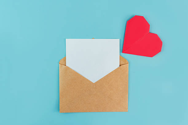 istock An envelope with a white blank sheet for writing and an origami heart on a blue background, a place for text 2210679423