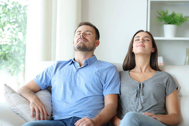 Couple relaxing at home breathing fresh air on a sofa