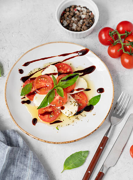 Fresh Caprese salad with sliced tomatoes, mozzarella cheese, basil leaves and balsamic glaze
