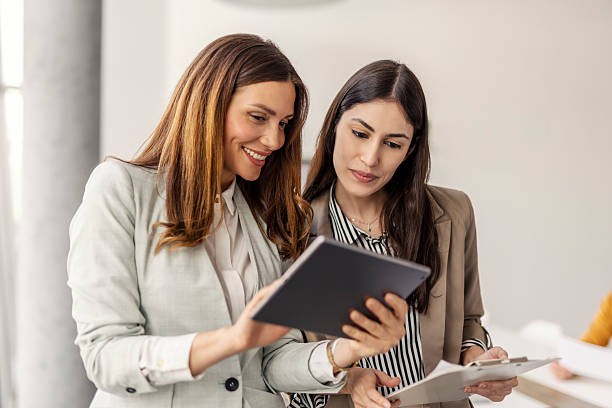 istock Portrait of smiling managers looking at tablet and discussing while standing at boardroom. 2210681308