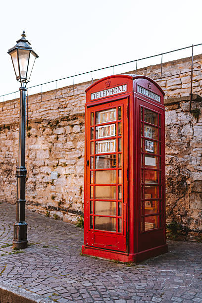 A red telephone booth is seen behind a rainy window