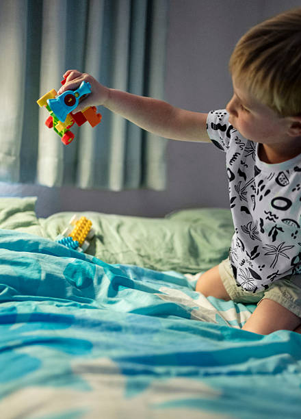 istock Young boy playing with toys on bed 2210682544