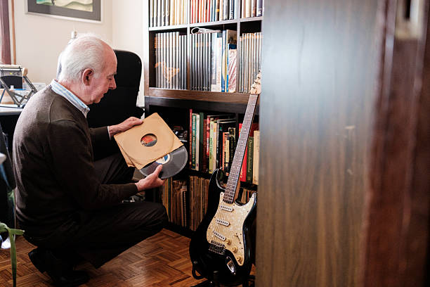 Senior man choosing vinyl record from collection at home