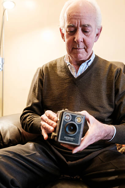 istock Senior man holding an old brownie camera at home 2210683400