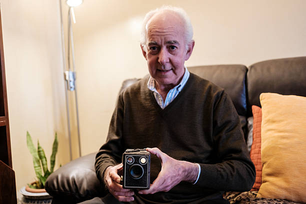istock Senior man holding a vintage box camera at home 2210683417