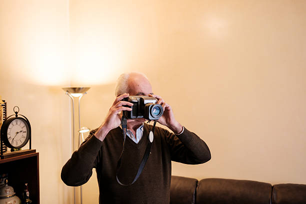 istock Senior man taking photos with old digital camera at home 2210683738