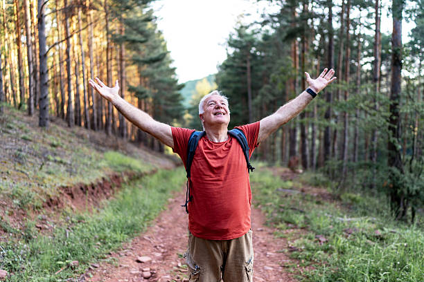 istock Senior hiker embracing nature with open arms in forest trail 2210686120