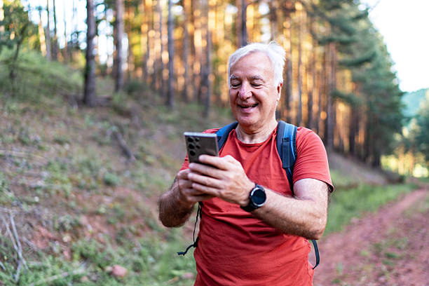 istock Senior man hiking in forest uses smartphone for navigation 2210686183