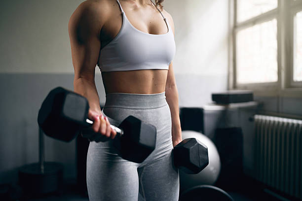 istock Young woman lifting dumbbells during a workout in a modern gym 2210688355