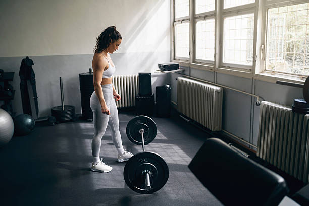istock Young woman preparing for workout with weights in a gym 2210688664