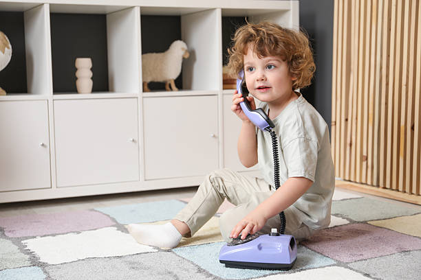 istock Cute little boy with telephone on floor indoors, space for text 2210691599