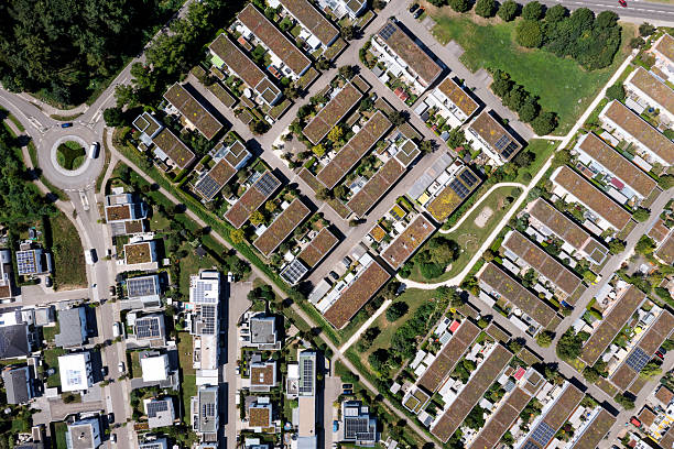 Aerial top down view of a residential district with houses, apartment buildings, streets, traffic circle and forest.