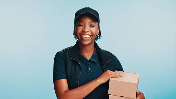 istock Black woman, box and portrait in studio for delivery, customer service and friendly for client care. Courier person, package and smile on blue background for logistics, supply chain or ecommerce 2210691986