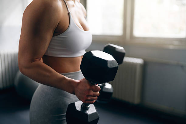 istock Strong woman lifting dumbbells during a gym workout 2210691996