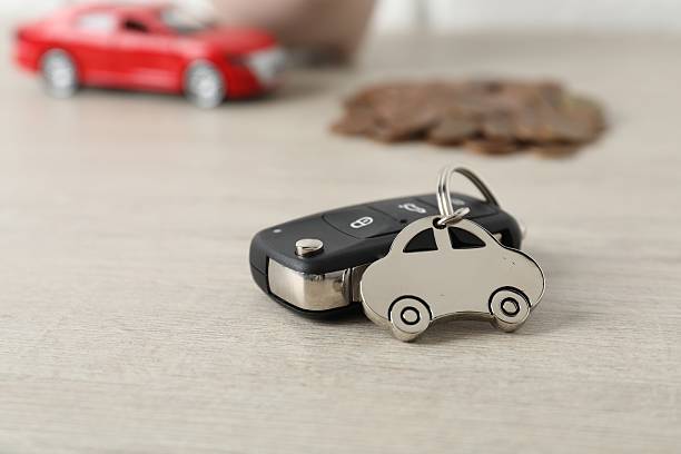 istock Car key with keychain on light wooden table, closeup. Buying auto 2210693054