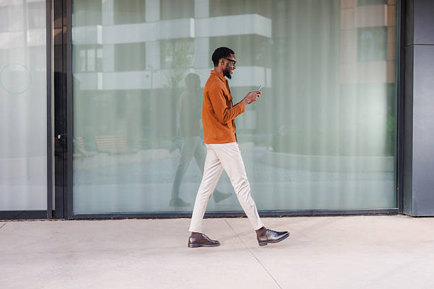 istock Man walking outside modern building using a smartphone in daytime 2210693171