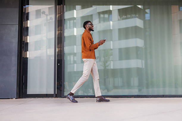 istock Styled Black man walking outside modern building using a smart phone 2210693199