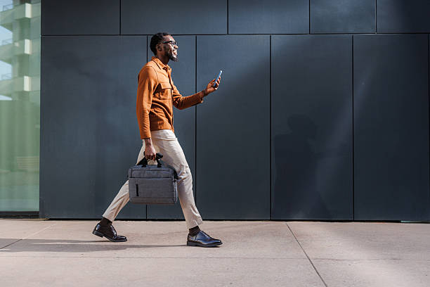 istock Professional walking confidently while using phone and carrying a laptop bag 2210693236