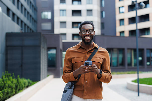 istock Portrait of a smiling Black man using smart phone outdoors in urban setting 2210693248