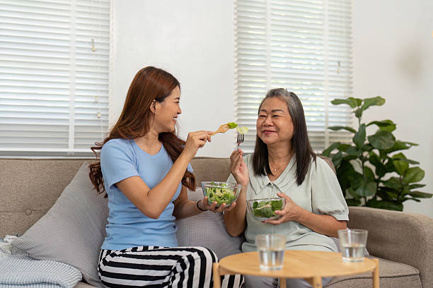 Wellness and Joyful Culinary Experiences. A mother and daughter share a light-hearted salad moment, embodying healthy living.