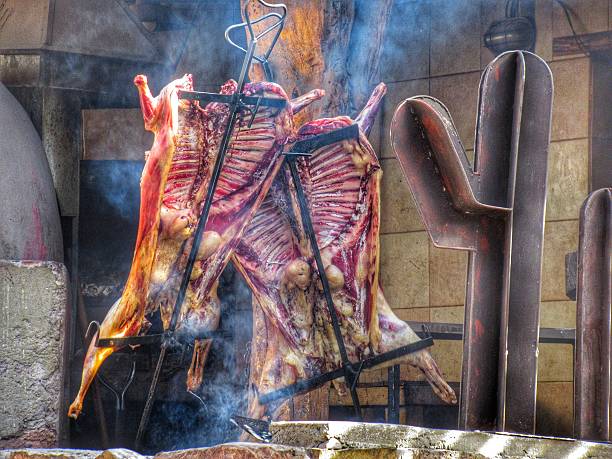 two lambs being roasted whole on a ground fire called a parrilla a typical local dish from San Francisco de Tilcara in the province of Jujuy in northern Argentina